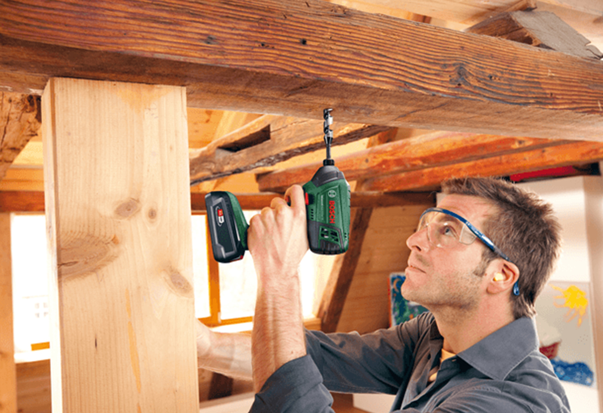 Απεικονίζεται άνδρας να χρησιμοποιεί το εργαλέιο για διάτρηση σε ξύλο.